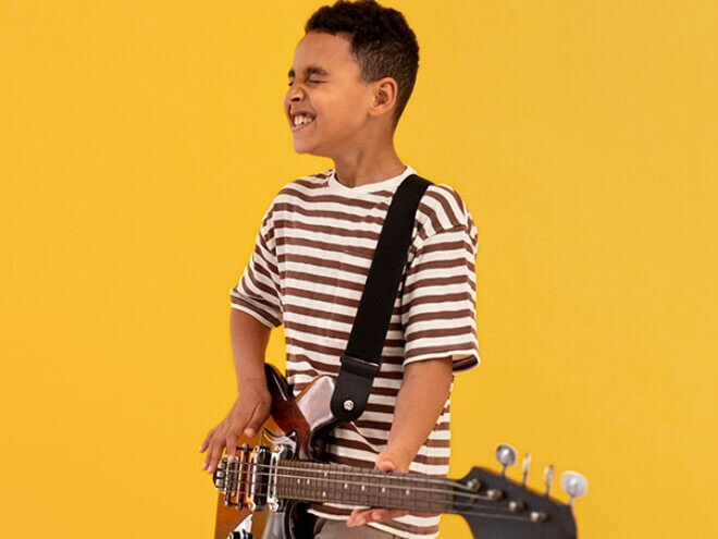 Menino usando camiseta listrada tocando guitarra.