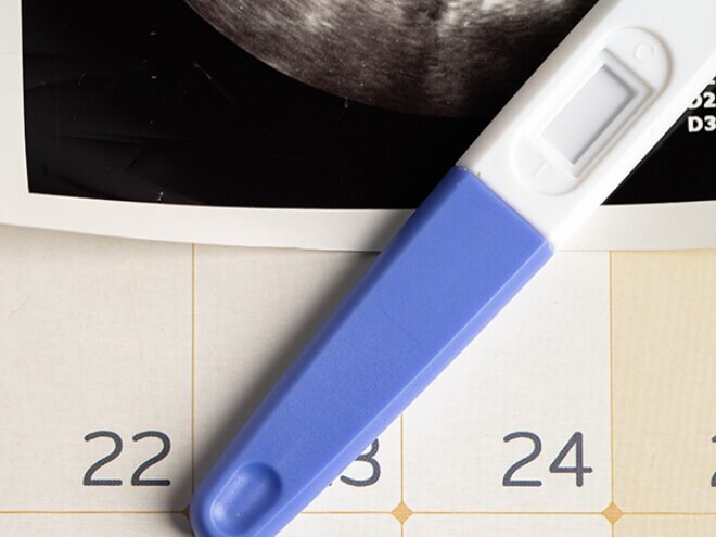 Imagem de um calendário com teste de gravidez e resultado de ultrassom.