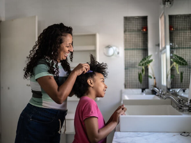 mulher faz tranças no cabelo de criança