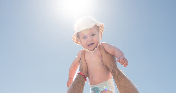 Um homem segundo com um sorriso no rosto contra o sol, em um dia quente de verão