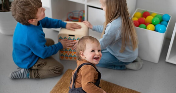 Crianças de diferentes idades brincando juntas ajoelhadas no chão.