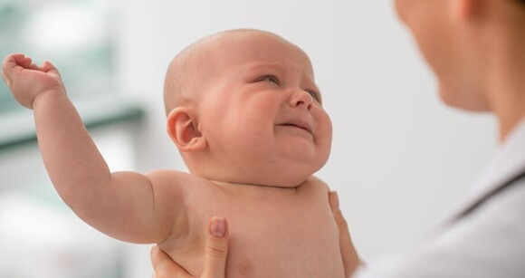 Bebê recém nascido chorando no colo de uma médica.