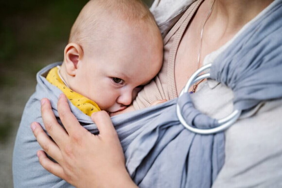 Um bebê no colo de uma mulher mamando