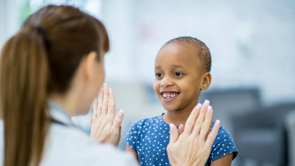 Menina sorrindo e brincando com uma enfermeira.