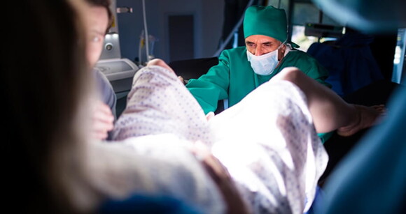 Médico realizando procedimento de cerclagem em paciente grávida