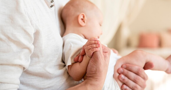 Homem embalando gentilmente um bebê no colo, mostrando o terno vínculo entre pai e filho