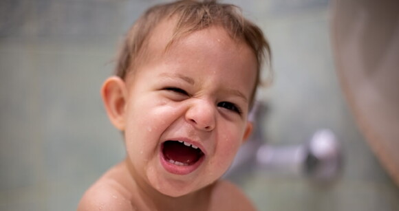 Bebê com diastema sorrindo enquanto toma banho de banheira.