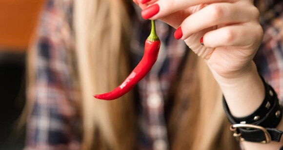 Imagem de uma mulher segurando uma pimenta vermelha