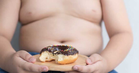 imagem de bebê segurando um donut representando obesidade infantil