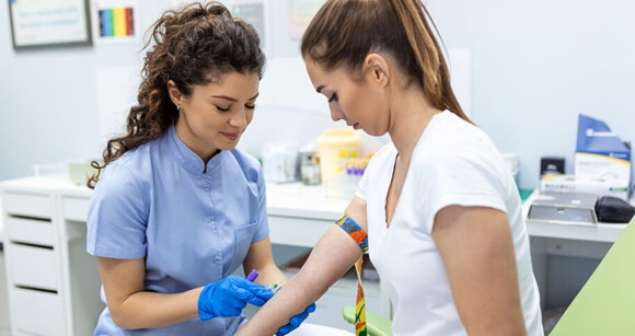 Imagem de uma enfermeira coletando amostras de sangue de uma mulher
