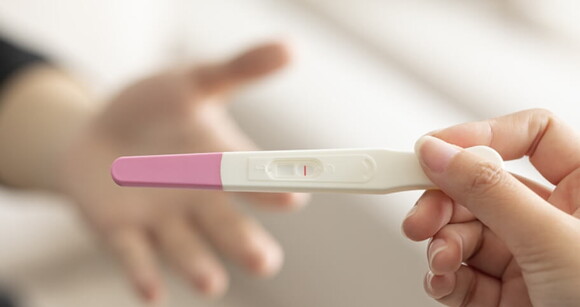 imagem de uma mão segurando um teste de gravidez