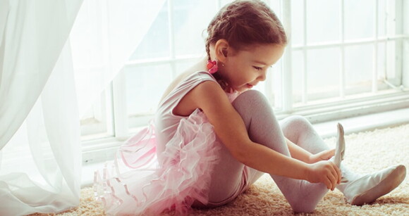 Menina com roupa de bailarina vestindo a sapatilha