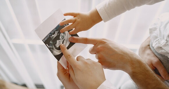 Mãos de membros da família apontando para a imagem de um ultrassom