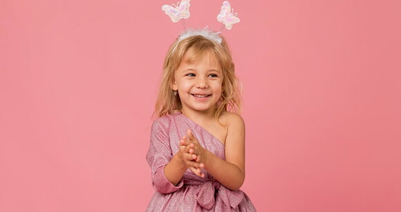 Menina loira sorrindo usando vestido cintilante e tiara de borboletas