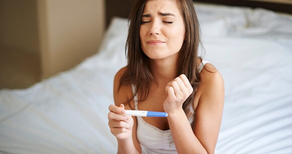 mulher apreensiva segurando teste de gravidez