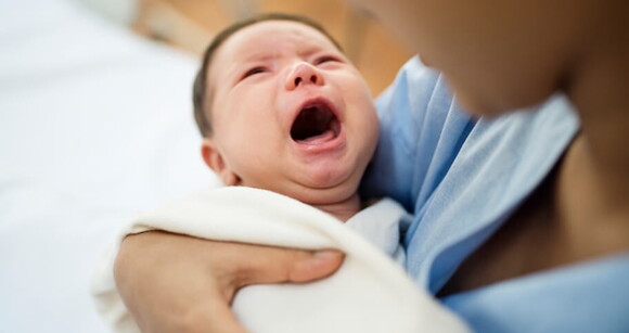 Mulher em um ambiente hospitalar com bebê chorando no colo