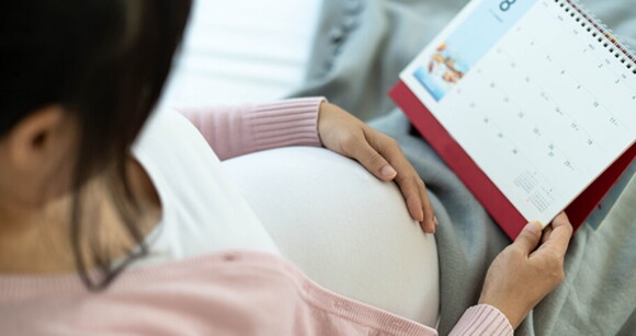 Mulher grávida sentada segurando um calendário