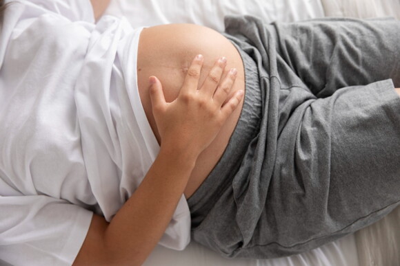 mulher grávida sentindo contrações de treinamento na cama