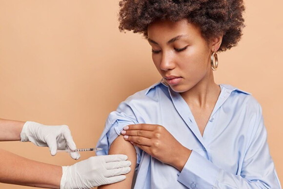 Mulher sentada recebendo injeção no braço