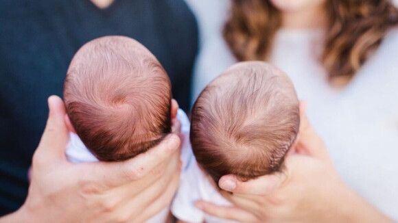 Um homem e uma mulher segurando dois bebês recém-nascidos.