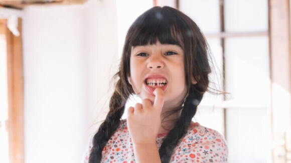 Menina apontando para um espaço vazio entre os seus dentes