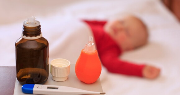 Bebê deitado no berço enquanto sua mãe prepara sua medicação.